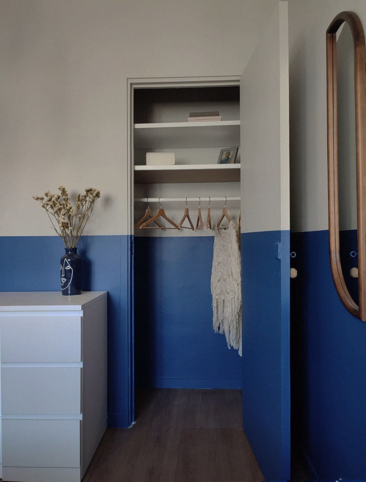 Exemple d'une chambre parentale blanche et bois méditerranéenne de taille moyenne avec un mur bleu, parquet foncé, aucune cheminée, un sol marron et dressing.