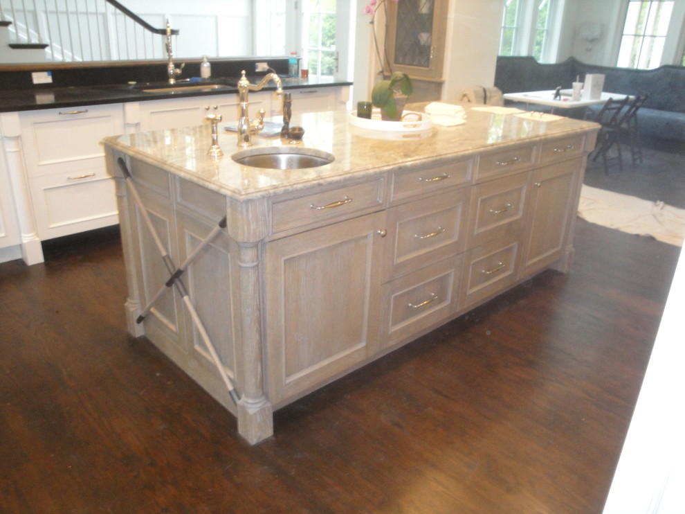 Inspiration for a mid-sized rustic l-shaped medium tone wood floor enclosed kitchen remodel in Chicago with an undermount sink, shaker cabinets, white cabinets, marble countertops, white backsplash, ceramic backsplash, stainless steel appliances and an island