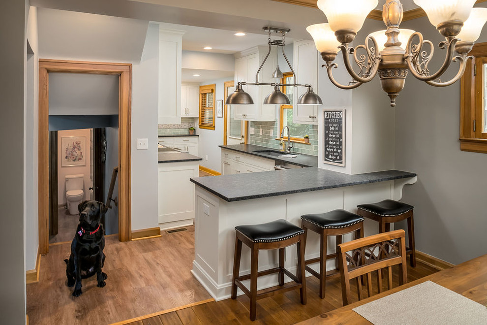 Mid-sized transitional galley vinyl floor and brown floor eat-in kitchen photo in Columbus with an undermount sink, shaker cabinets, white cabinets, granite countertops, green backsplash, ceramic backsplash, stainless steel appliances, a peninsula and black countertops