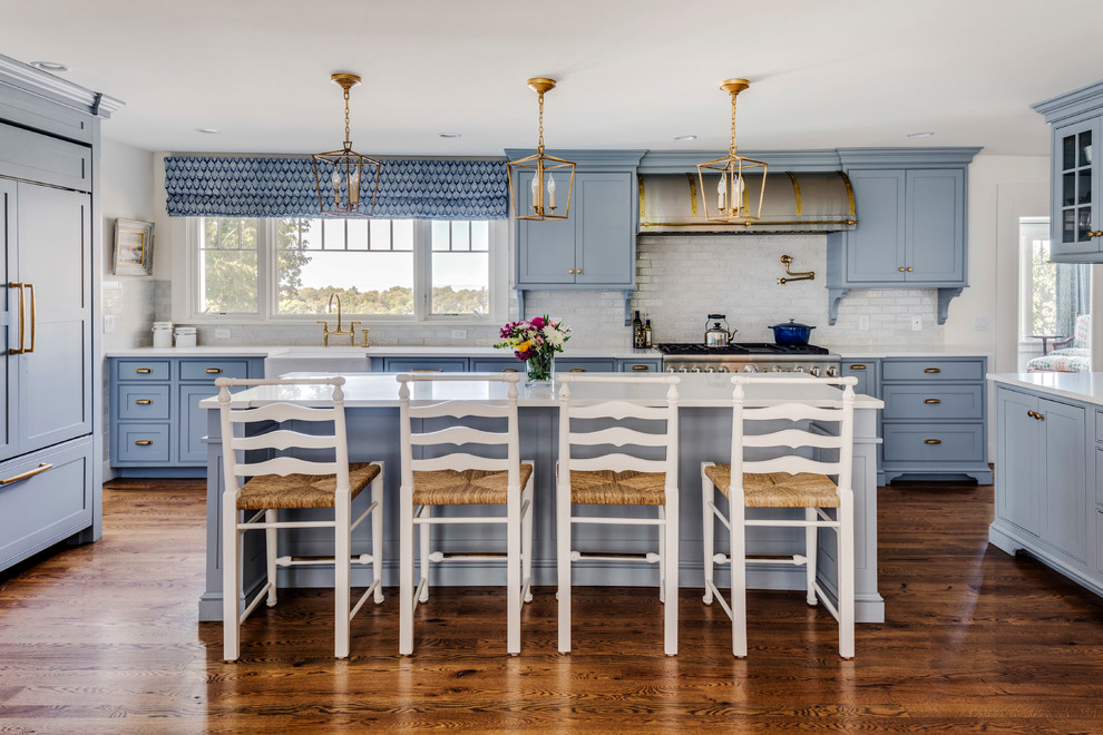 Large beach style kitchen in Boston with a farmhouse sink, shaker cabinets, white splashback, panelled appliances, dark hardwood floors, with island, brown floor, blue cabinets and subway tile splashback.