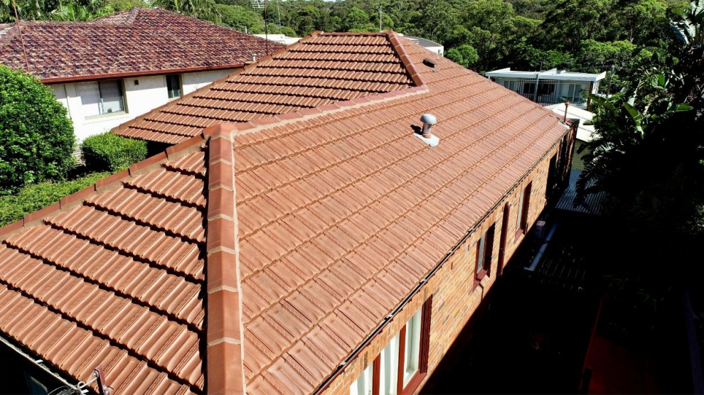 На фото: дом в классическом стиле с вальмовой крышей, крышей из смешанных материалов и красной крышей