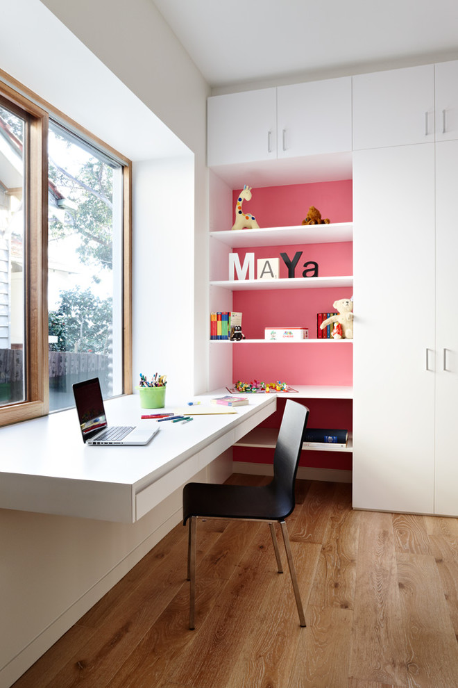 Mid-sized contemporary gender-neutral kids' study room in Melbourne with white walls and medium hardwood floors for kids 4-10 years old.