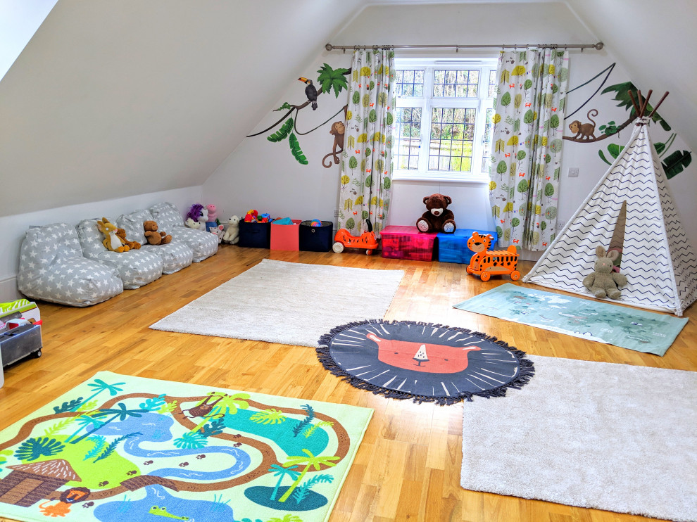 Photo of a large eclectic gender-neutral kids' room in London with white walls and laminate floors.
