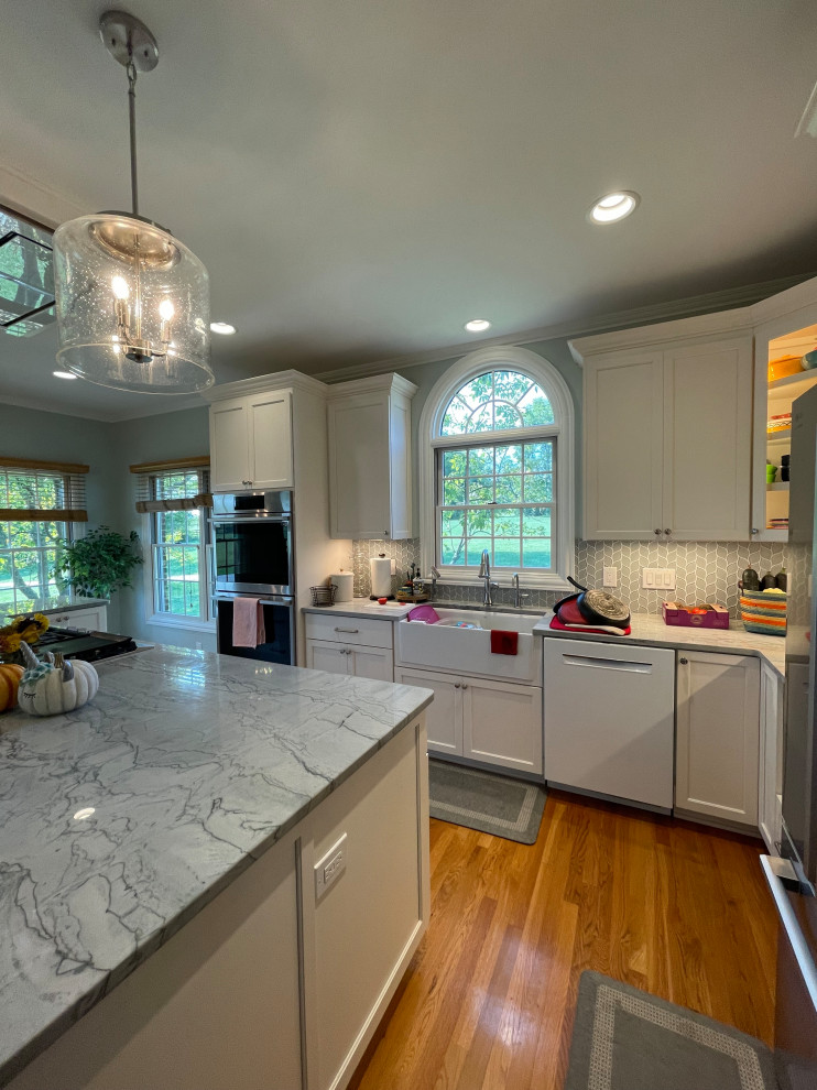 Large transitional light wood floor and brown floor eat-in kitchen photo with an undermount sink, shaker cabinets, white cabinets, quartzite countertops, green backsplash, marble backsplash, stainless steel appliances, an island and gray countertops