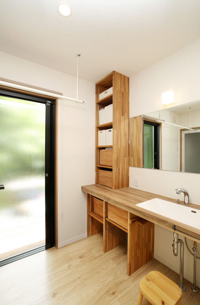 Gästetoilette mit verzierten Schränken, hellbraunen Holzschränken, weißer Wandfarbe, integriertem Waschbecken und brauner Waschtischplatte in Sonstige