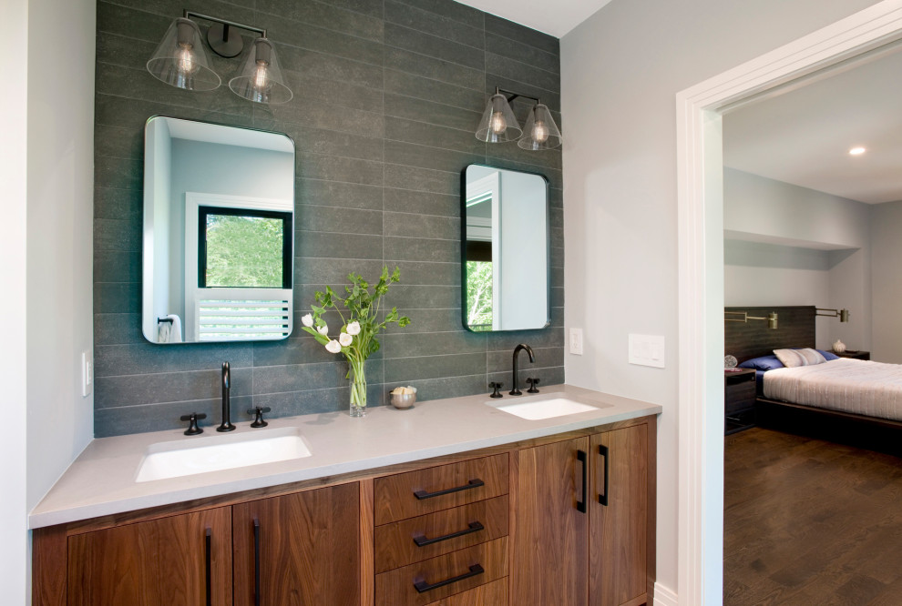 This is an example of a large transitional master bathroom in Boston with flat-panel cabinets, medium wood cabinets, a freestanding tub, black tile, grey walls, an undermount sink, engineered quartz benchtops, a hinged shower door, grey benchtops, a double vanity and a built-in vanity.