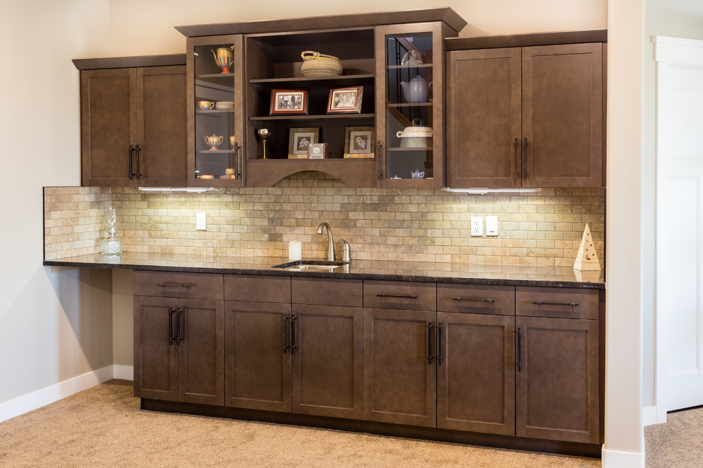 Design ideas for a mid-sized country single-wall wet bar in Calgary with an undermount sink, shaker cabinets, dark wood cabinets, granite benchtops, beige splashback, stone tile splashback and carpet.