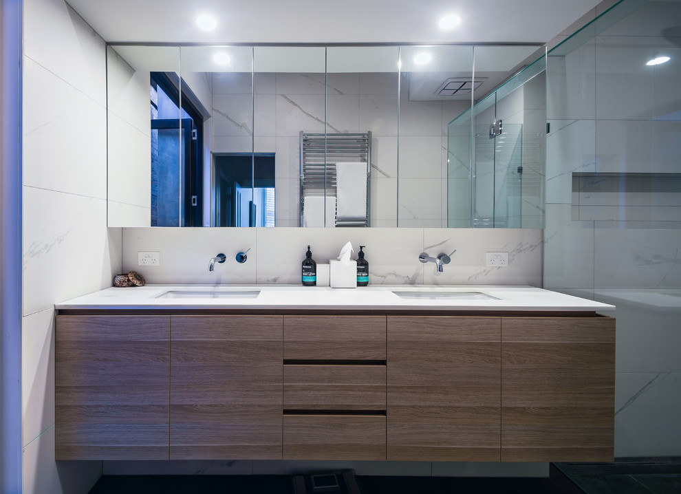 This is an example of a mid-sized modern master bathroom in Melbourne with flat-panel cabinets, medium wood cabinets, a wall-mount toilet, gray tile, porcelain tile, white walls, an undermount sink and engineered quartz benchtops.