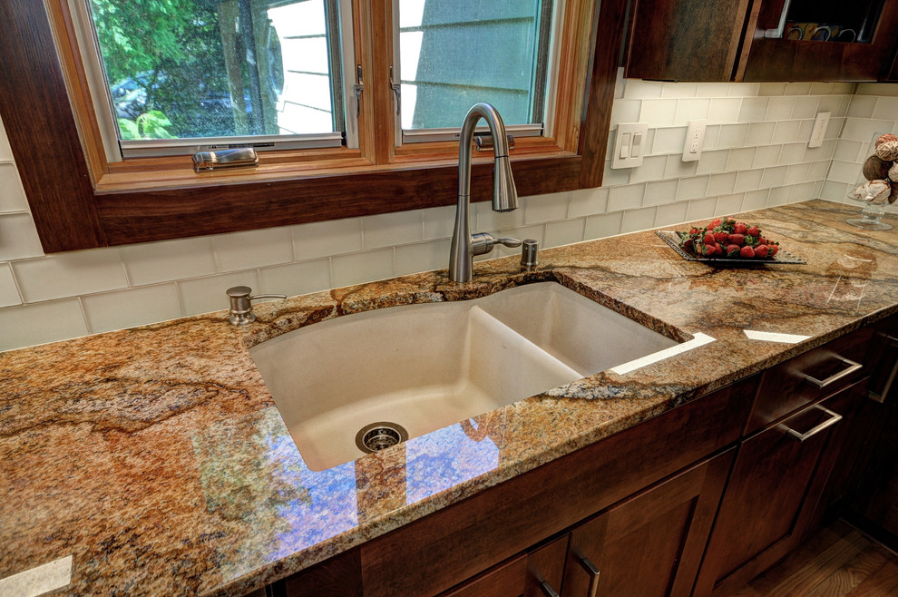 Large transitional l-shaped light wood floor enclosed kitchen photo in Milwaukee with an undermount sink, shaker cabinets, medium tone wood cabinets, granite countertops, beige backsplash, glass tile backsplash, stainless steel appliances and an island