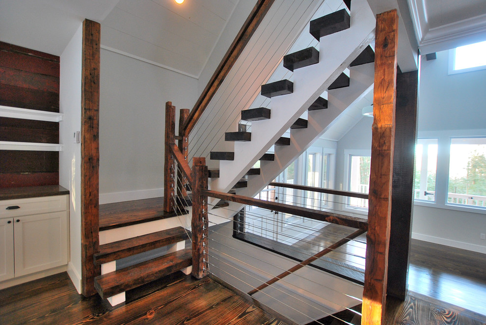 Country wood staircase in New York with open risers and cable railing.