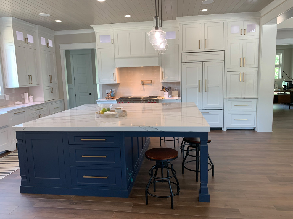 Photo of an expansive transitional u-shaped open plan kitchen in Other with a farmhouse sink, flat-panel cabinets, white cabinets, quartz benchtops, grey splashback, stainless steel appliances, vinyl floors, with island, brown floor, white benchtop and timber.