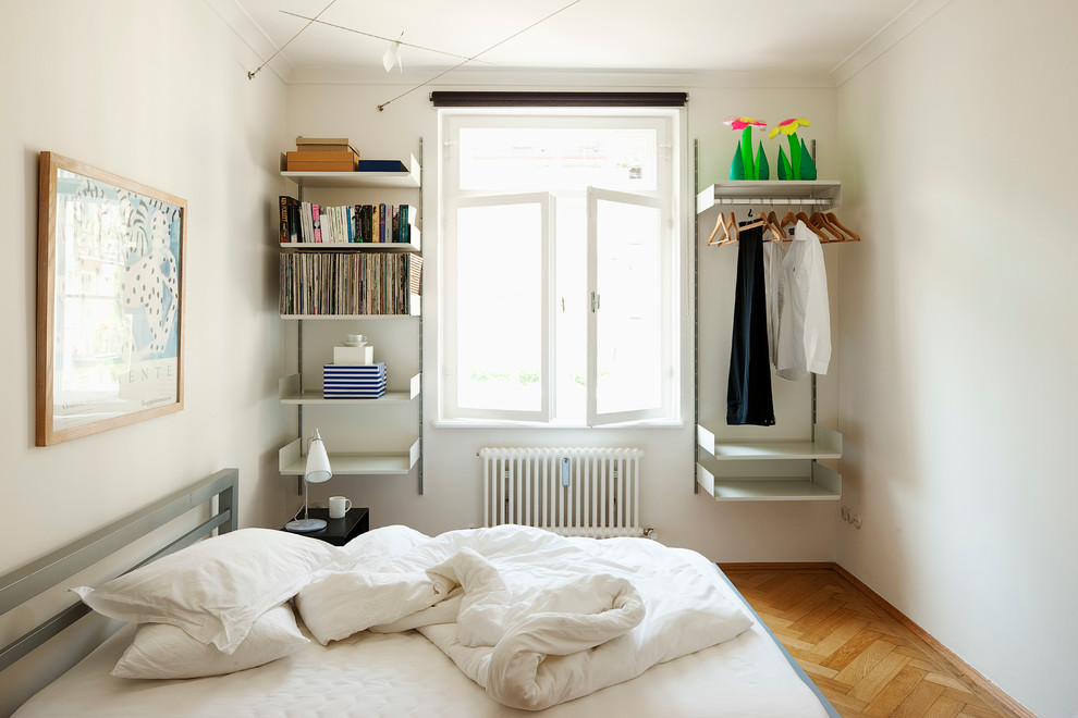 Schlafzimmer ohne Kamin mit weißer Wandfarbe und braunem Holzboden in Munich