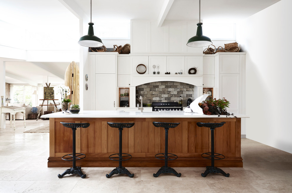 Inspiration for a large country galley kitchen in Sydney with a farmhouse sink, shaker cabinets, white cabinets, quartz benchtops, grey splashback, stone tile splashback, black appliances, travertine floors, with island, grey floor and white benchtop.