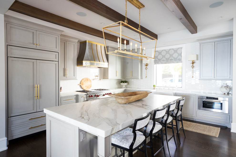 Inspiration for a transitional kitchen in Other with a farmhouse sink, beaded inset cabinets, grey cabinets, marble benchtops, white splashback, ceramic splashback, panelled appliances, dark hardwood floors, brown floor and white benchtop.