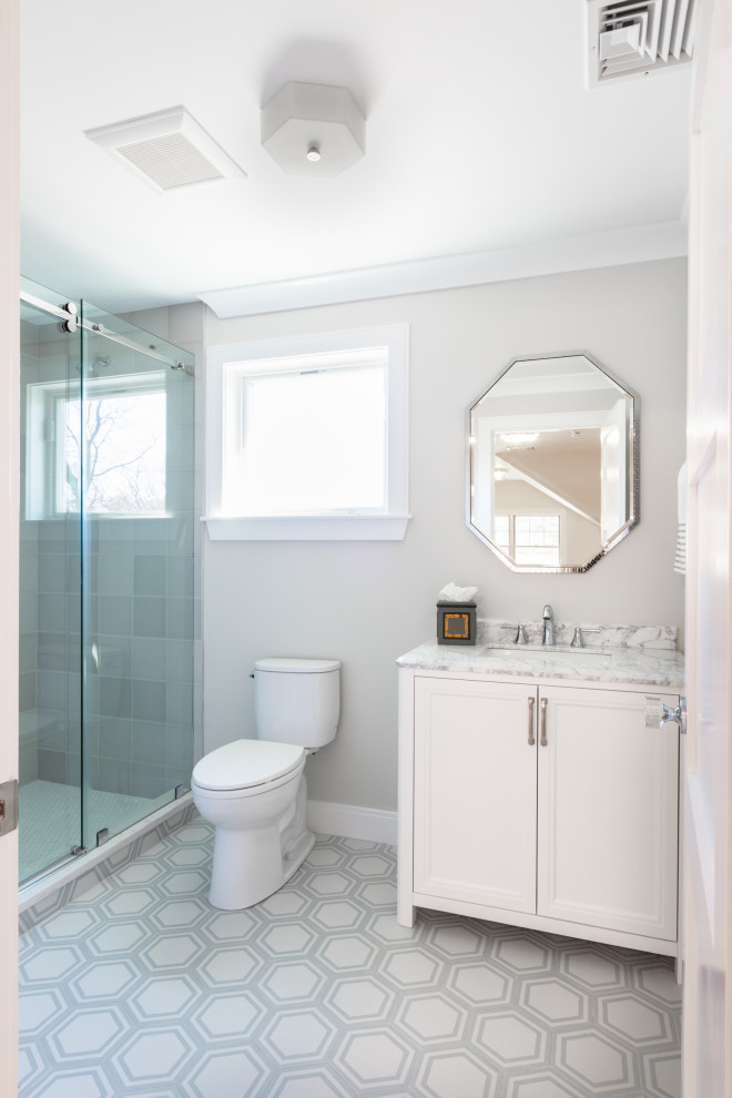 This is an example of a mid-sized transitional 3/4 bathroom in Boston with shaker cabinets, white cabinets, an alcove shower, a two-piece toilet, gray tile, porcelain tile, grey walls, ceramic floors, an undermount sink, marble benchtops, multi-coloured floor, a sliding shower screen, white benchtops, a niche, a single vanity and a freestanding vanity.