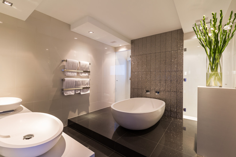 Contemporary bathroom in Melbourne with a vessel sink, a freestanding tub and gray tile.