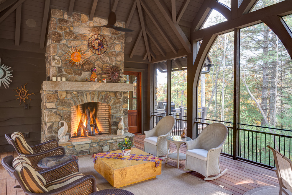 Photo of a large country sunroom in Other with medium hardwood floors, a standard fireplace, a stone fireplace surround and a standard ceiling.