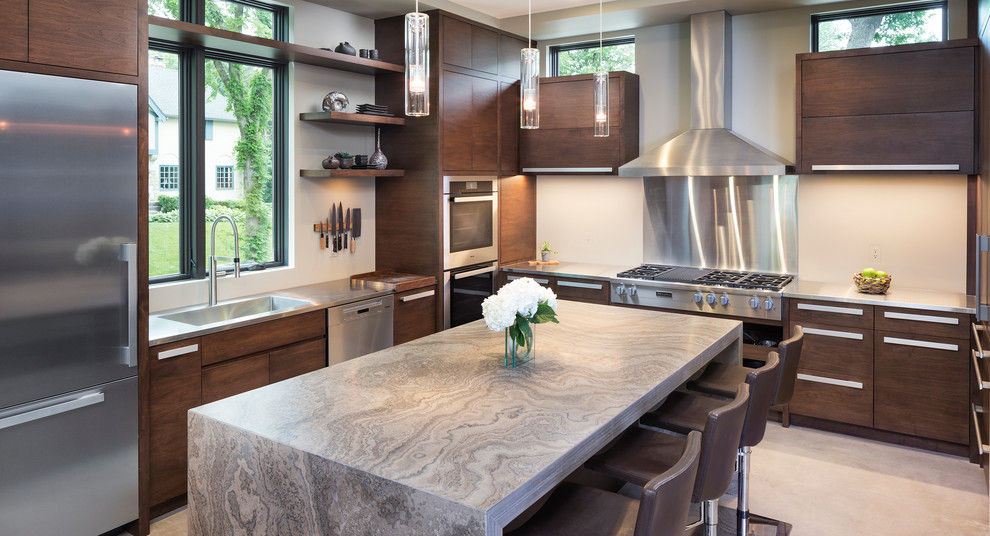 Inspiration for a small modern kitchen in Minneapolis with flat-panel cabinets, limestone benchtops, beige splashback, stainless steel appliances, concrete floors, with island and dark wood cabinets.