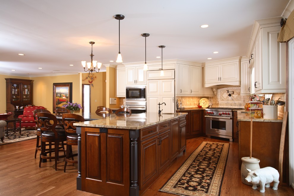 Design ideas for a large traditional l-shaped open plan kitchen in Minneapolis with an undermount sink, raised-panel cabinets, dark wood cabinets, granite benchtops, beige splashback, stone tile splashback, panelled appliances, medium hardwood floors and with island.