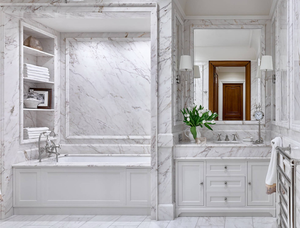 Стильный дизайн: главная ванная комната в классическом стиле с фасадами с утопленной филенкой, белыми фасадами, ванной в нише, белой плиткой, врезной раковиной, белым полом, белой столешницей и тумбой под одну раковину - последний тренд