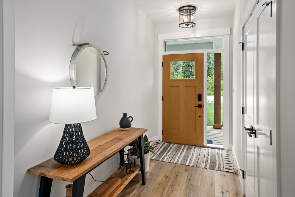This is an example of a mid-sized country entry hall in Vancouver with grey walls, laminate floors, a pivot front door, a medium wood front door and brown floor.