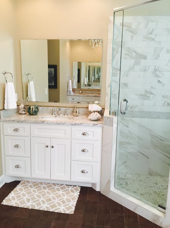 Inspiration for a mid-sized transitional master bathroom in Other with an undermount sink, recessed-panel cabinets, white cabinets, a corner shower, white tile, porcelain tile, porcelain floors, a freestanding tub, granite benchtops, a one-piece toilet, beige walls, brown floor, a hinged shower door and multi-coloured benchtops.