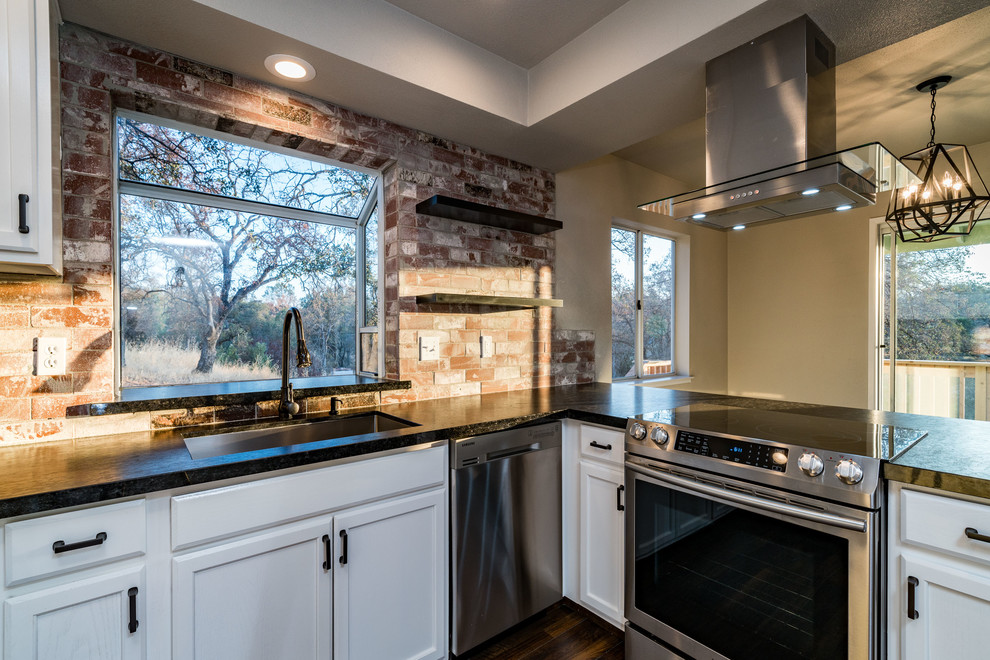 Inspiration for a mid-sized transitional u-shaped dark wood floor and brown floor enclosed kitchen remodel with a triple-bowl sink, recessed-panel cabinets, white cabinets, granite countertops, red backsplash, brick backsplash, stainless steel appliances and a peninsula