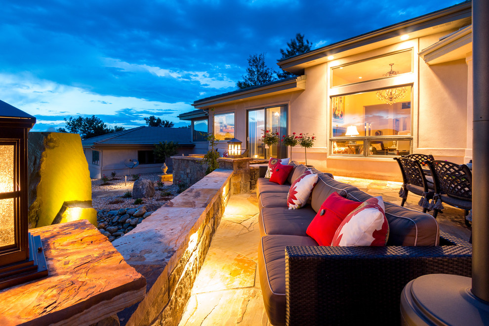 This is an example of an expansive traditional backyard patio in Denver with natural stone pavers and a roof extension.