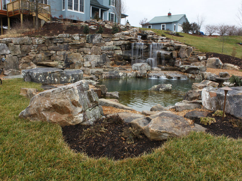 Photo of a country side yard custom-shaped natural pool in Other with a water feature and natural stone pavers.
