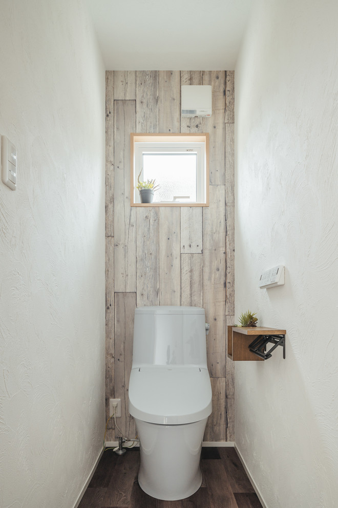 Bild på ett litet toalett, med en toalettstol med hel cisternkåpa och vita väggar