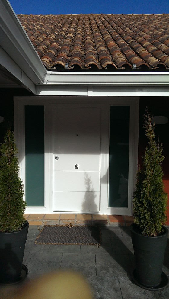 Foto de puerta principal moderna grande con paredes rojas, puerta simple, puerta blanca y suelo de pizarra