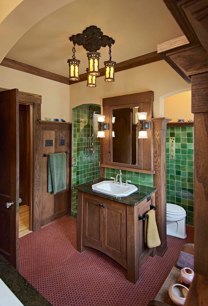 This is an example of an arts and crafts bathroom in Minneapolis with a drop-in sink, dark wood cabinets, green tile, shaker cabinets, red floor and green benchtops.