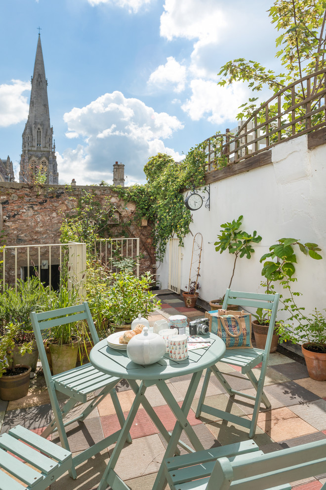 This is an example of a small eclectic patio in Devon with a potted garden and tiled flooring.