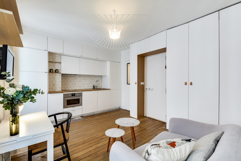 Design ideas for a mid-sized contemporary single-wall eat-in kitchen in Paris with an undermount sink, beaded inset cabinets, white cabinets, wood benchtops, white splashback, ceramic splashback, panelled appliances, light hardwood floors and no island.