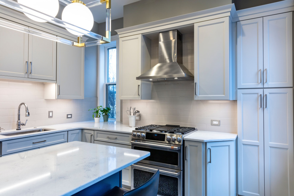 Example of a transitional porcelain tile kitchen design with white backsplash, ceramic backsplash, stainless steel appliances, an island and white countertops