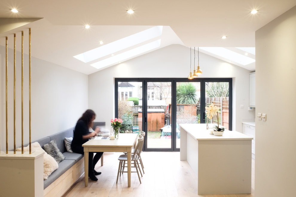 This is an example of a mid-sized contemporary open plan dining in Sussex with grey walls, light hardwood floors and brown floor.