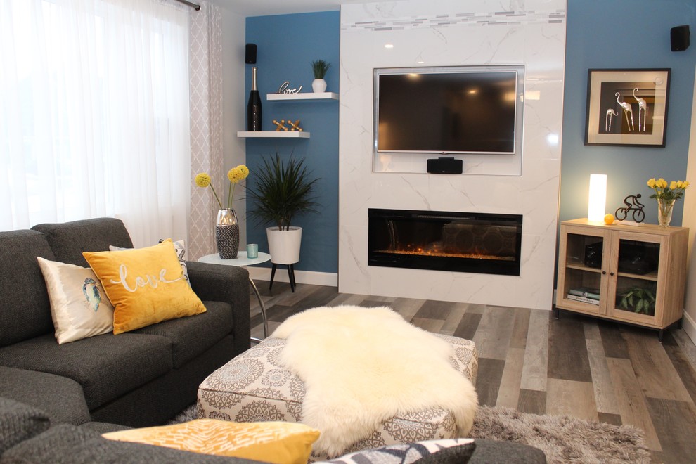 Design ideas for a mid-sized modern open concept living room in Calgary with blue walls, laminate floors, a standard fireplace, a tile fireplace surround, a built-in media wall and grey floor.