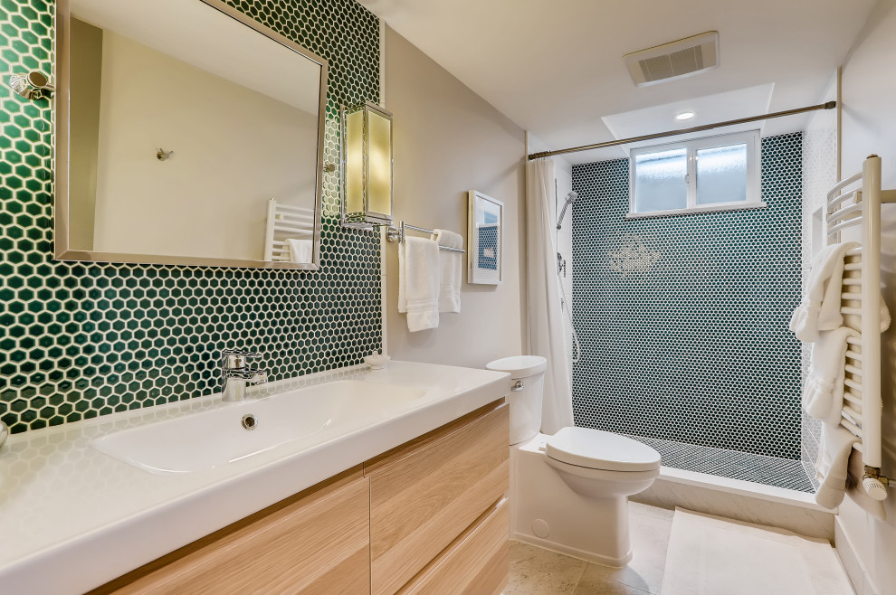 This is an example of a medium sized contemporary shower room bathroom in Denver with flat-panel cabinets, light wood cabinets, an alcove shower, a one-piece toilet, green tiles, mosaic tiles, white walls, porcelain flooring, an integrated sink, solid surface worktops, grey floors, a shower curtain, white worktops, a wall niche, a single sink and a floating vanity unit.