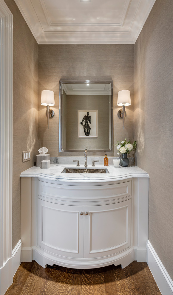 Inspiration for a transitional powder room in Boston with recessed-panel cabinets, white cabinets, grey walls, medium hardwood floors, an undermount sink, marble benchtops, grey benchtops, a built-in vanity, recessed and wallpaper.