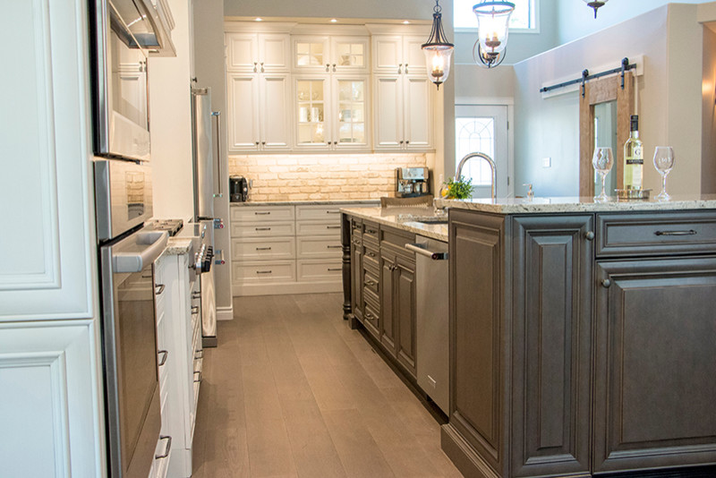 Inspiration for a large transitional l-shaped eat-in kitchen remodel with a double-bowl sink, shaker cabinets, white cabinets, beige backsplash, stainless steel appliances and an island