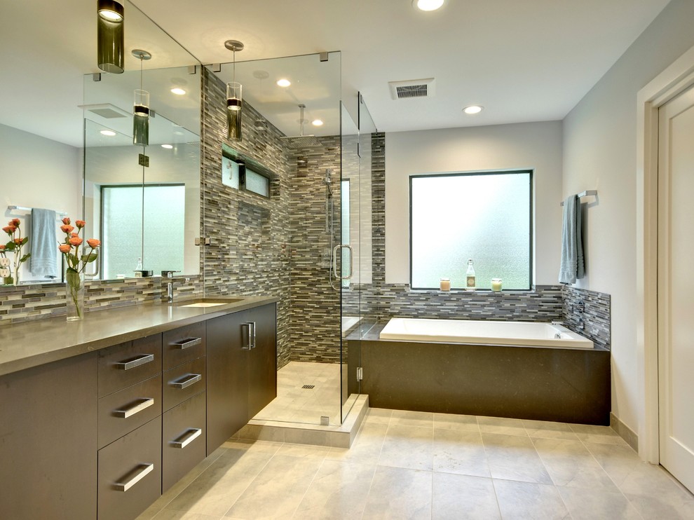 Design ideas for a mid-sized contemporary master bathroom in Austin with flat-panel cabinets, dark wood cabinets, a drop-in tub, a corner shower, grey walls, an undermount sink, a two-piece toilet, beige tile, brown tile, gray tile, matchstick tile, slate floors, solid surface benchtops, beige floor and a hinged shower door.
