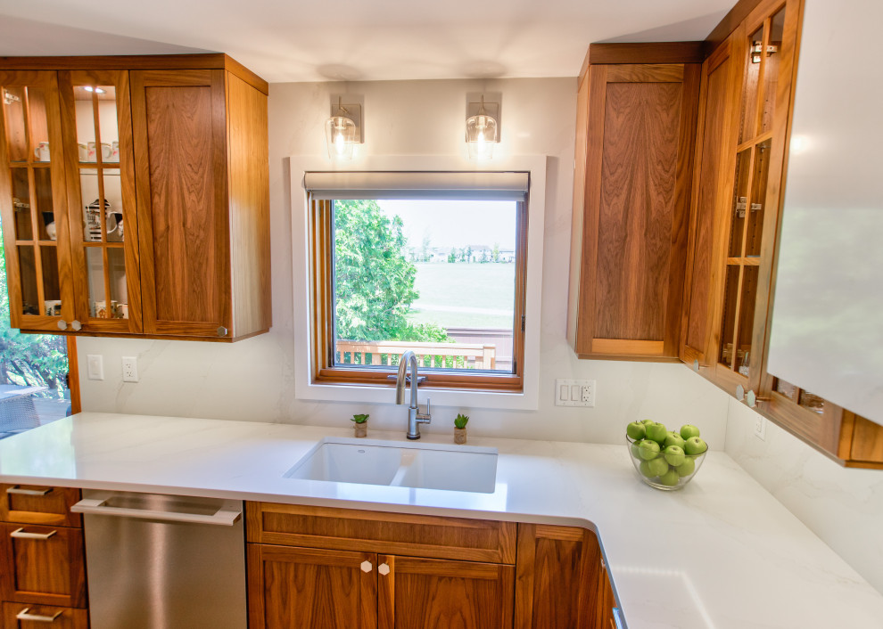 Inspiration for a mid-sized transitional u-shaped light wood floor and gray floor eat-in kitchen remodel with an undermount sink, shaker cabinets, brown cabinets, quartz countertops, white backsplash, quartz backsplash, stainless steel appliances, no island and white countertops