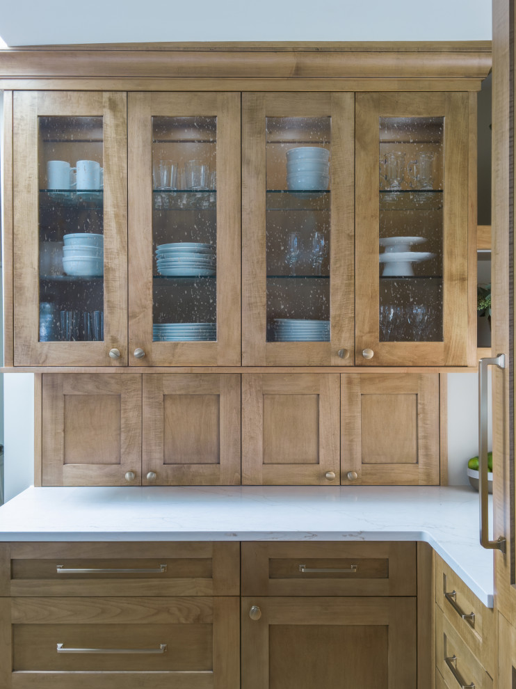 Inspiration for a mid-sized transitional l-shaped medium tone wood floor and brown floor open concept kitchen remodel in Chicago with an undermount sink, glass-front cabinets, medium tone wood cabinets, quartz countertops, white backsplash, ceramic backsplash, stainless steel appliances, an island and white countertops