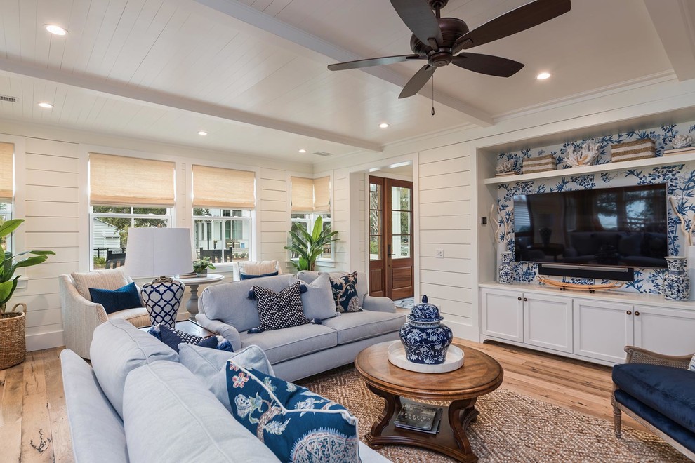 Photo of a large beach style open concept living room in Atlanta with white walls, light hardwood floors, a standard fireplace, a brick fireplace surround, a wall-mounted tv and brown floor.