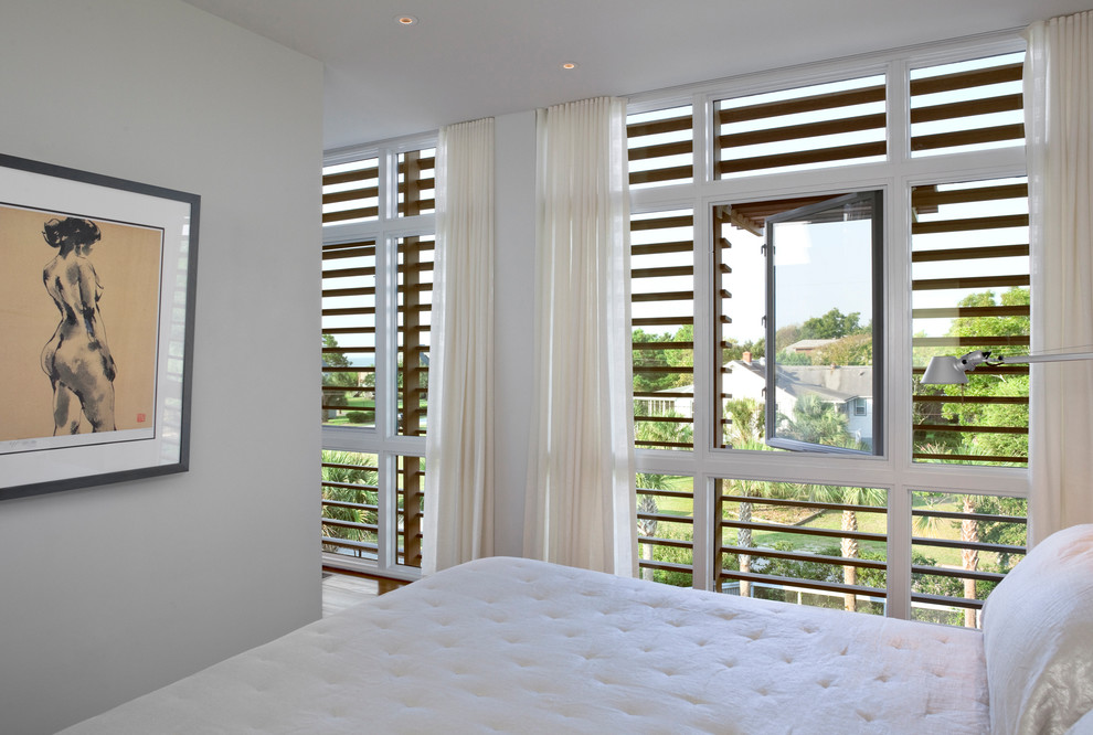 This is an example of a small modern guest bedroom in Charleston with white walls and medium hardwood floors.