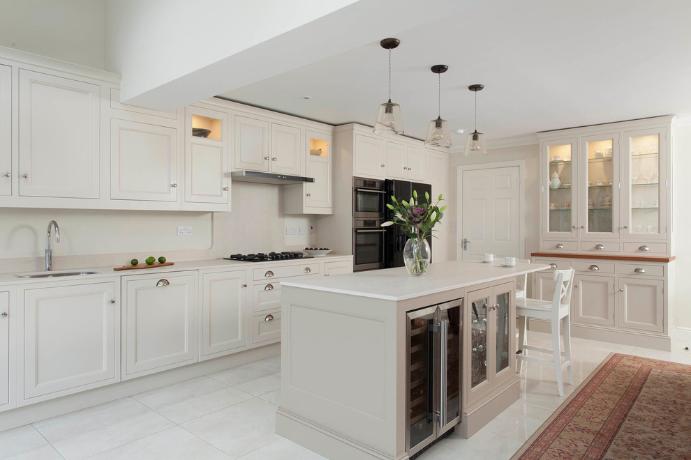 Design ideas for a large classic single-wall open plan kitchen in Dublin with a submerged sink, beaded cabinets, beige cabinets, quartz worktops, beige splashback, stone slab splashback, stainless steel appliances, porcelain flooring and an island.