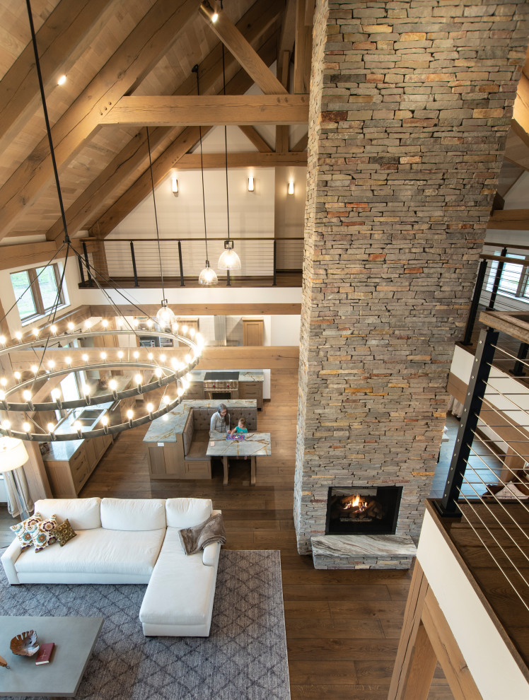 Design ideas for a large country open concept living room in Other with a two-sided fireplace, a stone fireplace surround and exposed beam.