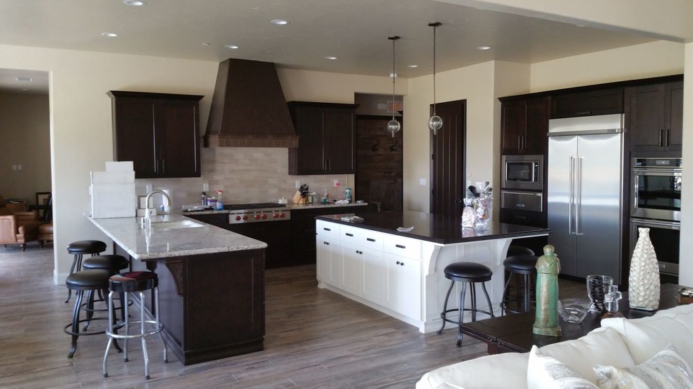 Inspiration for a large transitional u-shaped brown floor open concept kitchen remodel with an undermount sink, recessed-panel cabinets, dark wood cabinets, granite countertops, beige backsplash, porcelain backsplash, stainless steel appliances and an island