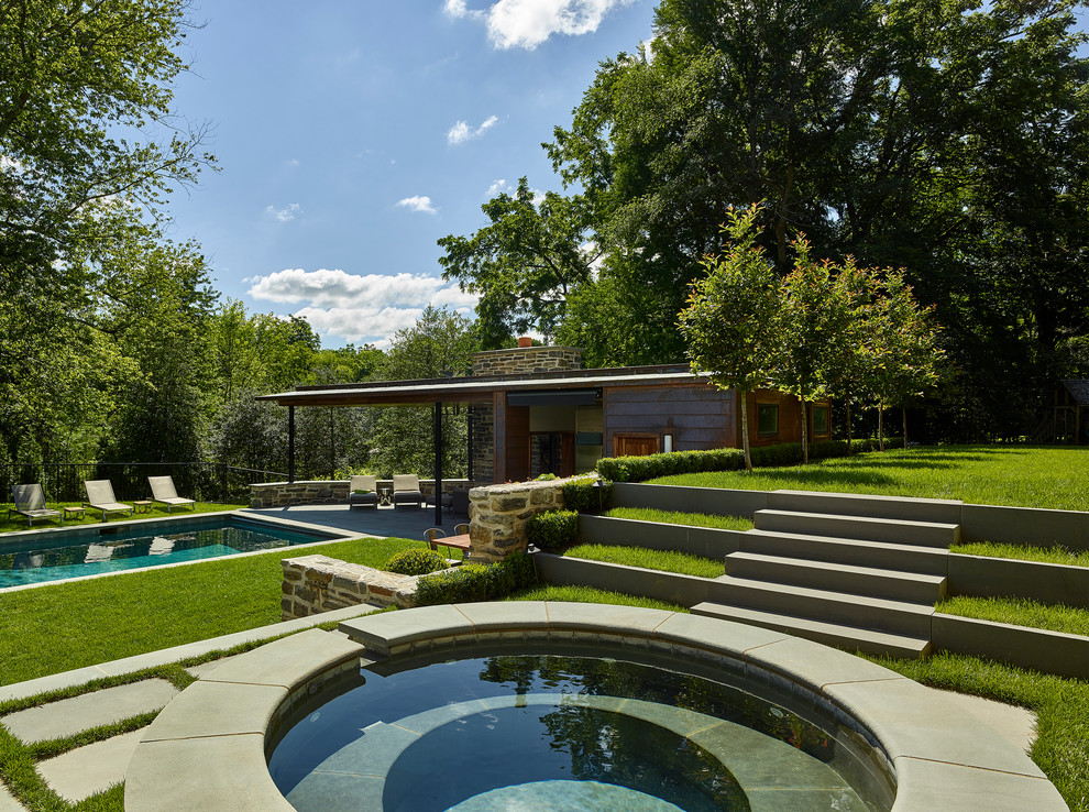 Design ideas for a contemporary backyard rectangular pool in Philadelphia with natural stone pavers and a hot tub.