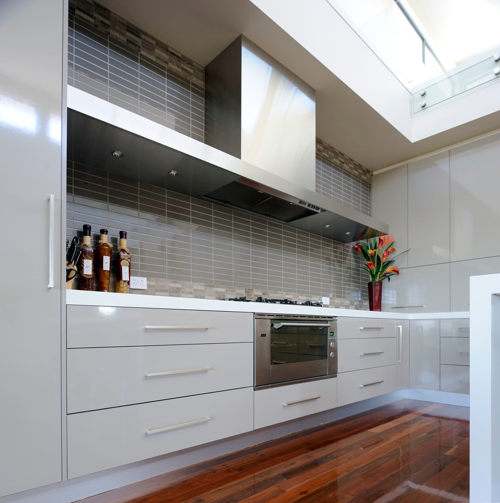 This is an example of a large contemporary l-shaped kitchen pantry in Melbourne with an undermount sink, flat-panel cabinets, grey cabinets, grey splashback, ceramic splashback, stainless steel appliances, dark hardwood floors and with island.